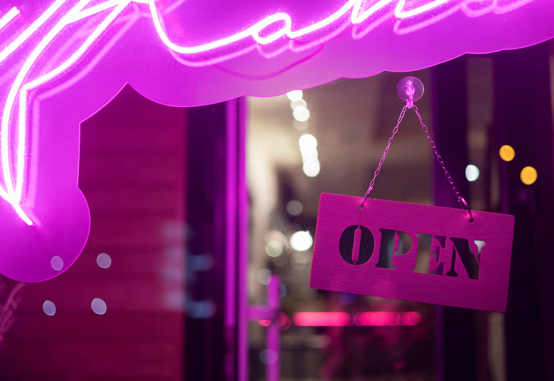 Neon open sign hanging in a window with purple light